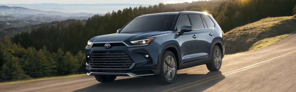 Gray SUV driving on a scenic mountain road at sunset.