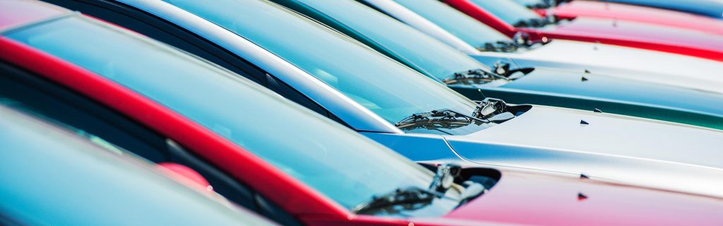 Row of colorful cars parked in a dealership lot.