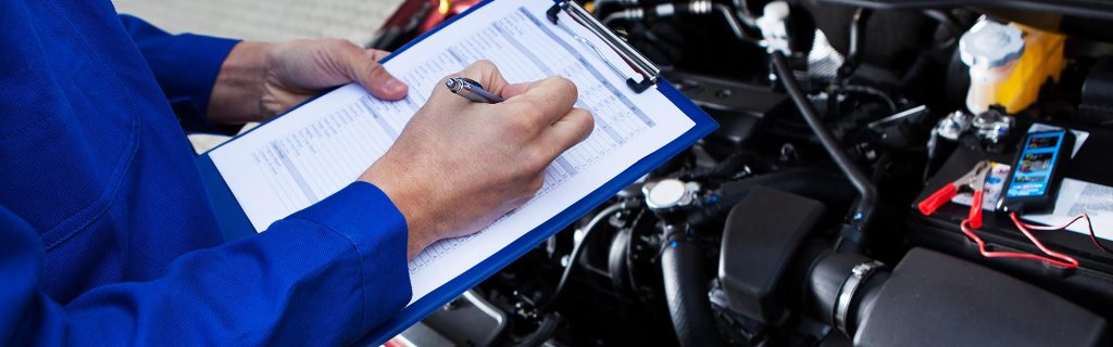 Mechanic filling out a vehicle inspection checklist.