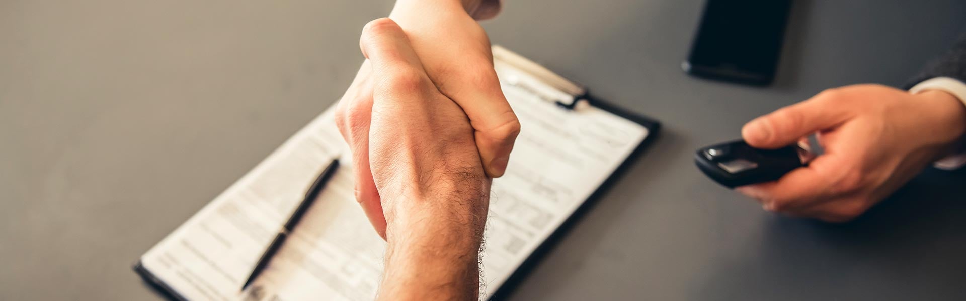 Handshake over car purchase paperwork as keys are handed over