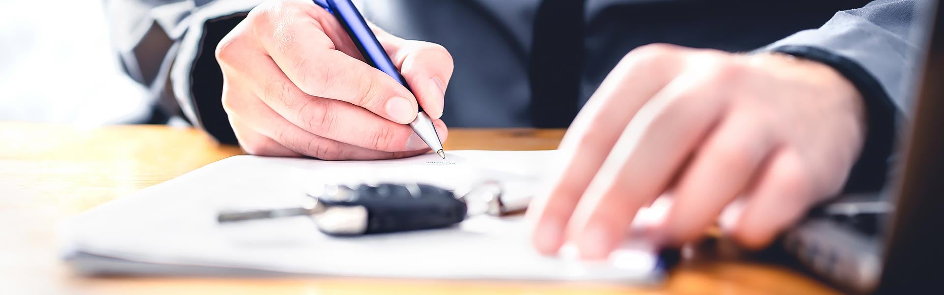 Person signing a document next to a car key fob